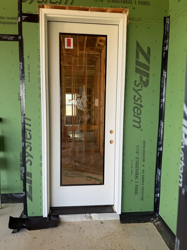 White full-glass door set into ZIP System sheathing on a new build, flashed and ready for trim