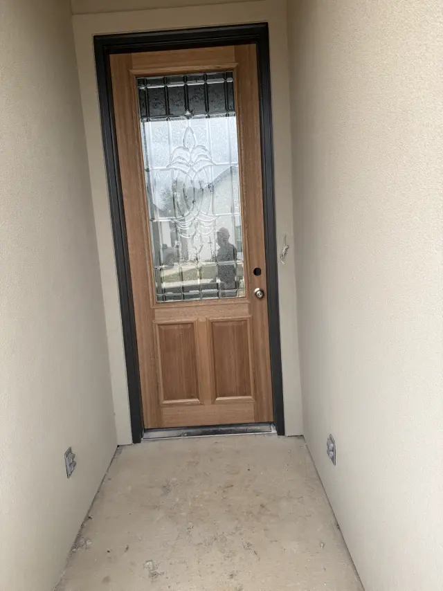 Wood entry door with decorative leaded glass, installed in a recessed entryway