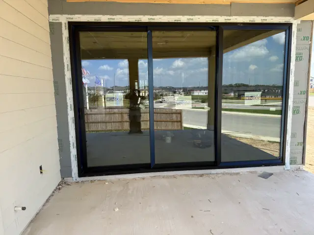 Black three-panel sliding patio door installed facing a covered back patio