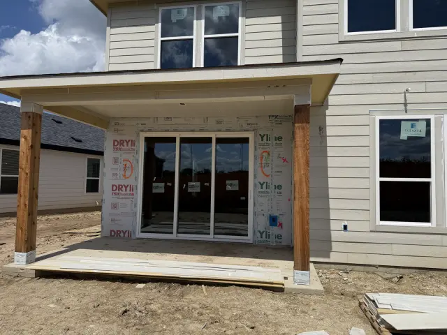 New home exterior showing an installed sliding patio door under a covered porch with cedar posts