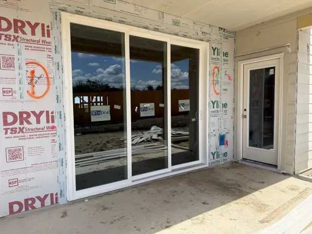 White three-panel sliding door and a matching full-glass side door installed on a new build