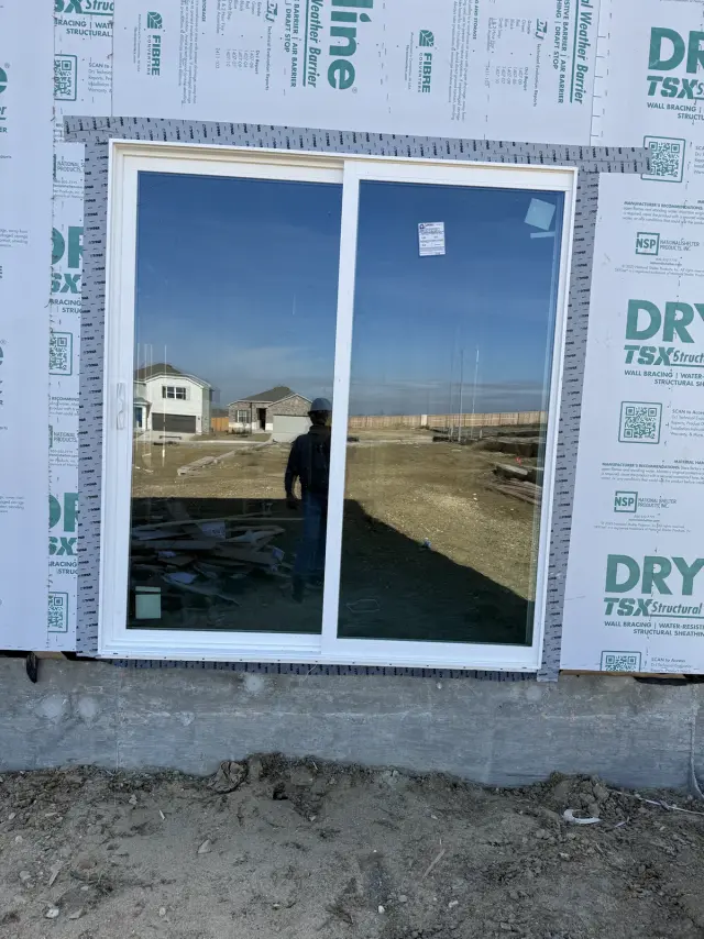 White two-panel sliding patio door installed on a new home with house wrap