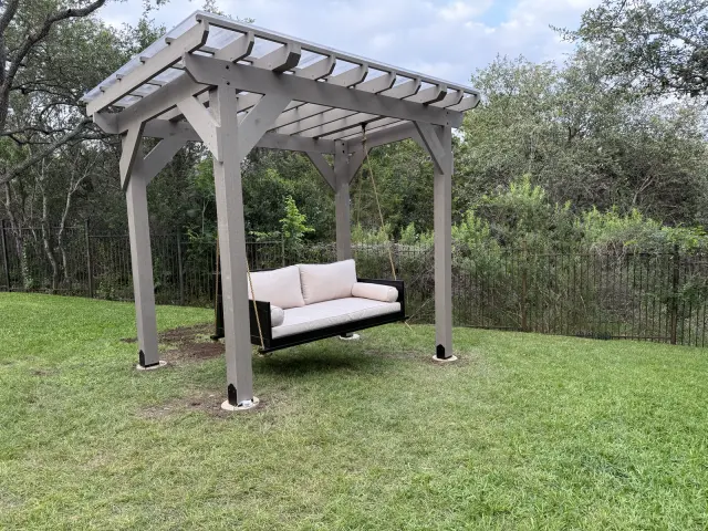 Painted cedar pergola with a hanging bed swing in a San Antonio backyard